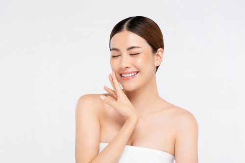 Youthful bright skin pretty Asian woman with hand touching face and eyes closing on white background for beauty concepts